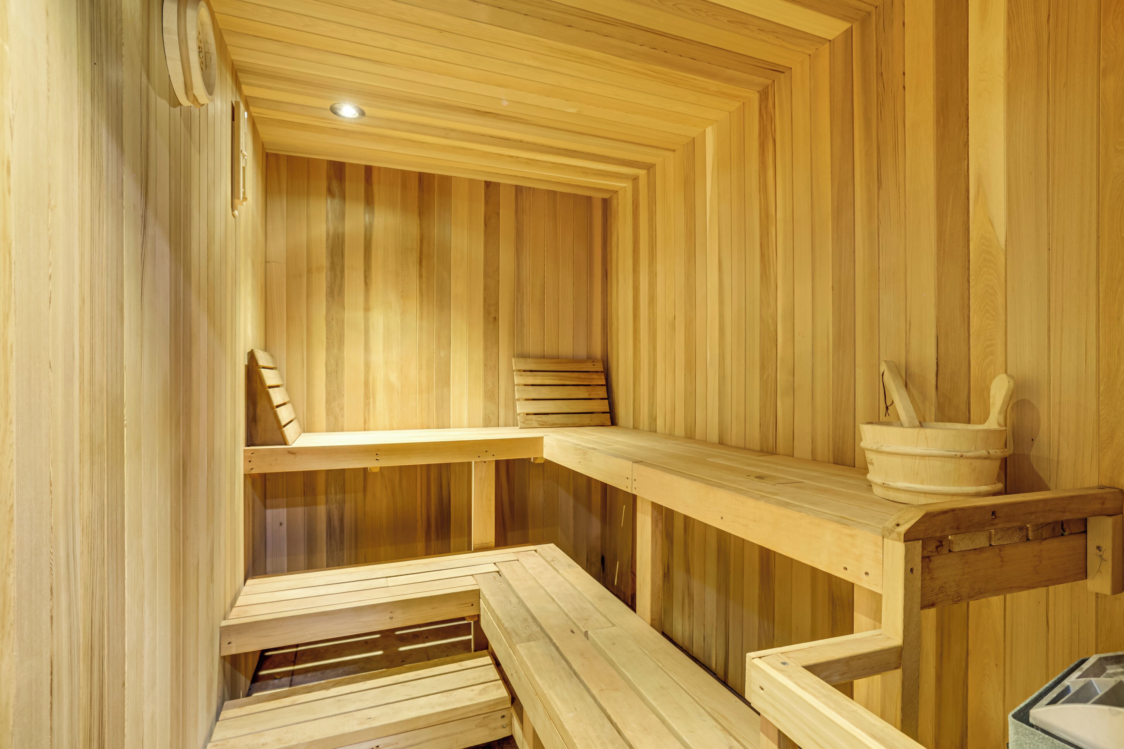 A wooden sauna with benches and a wooden bucket.