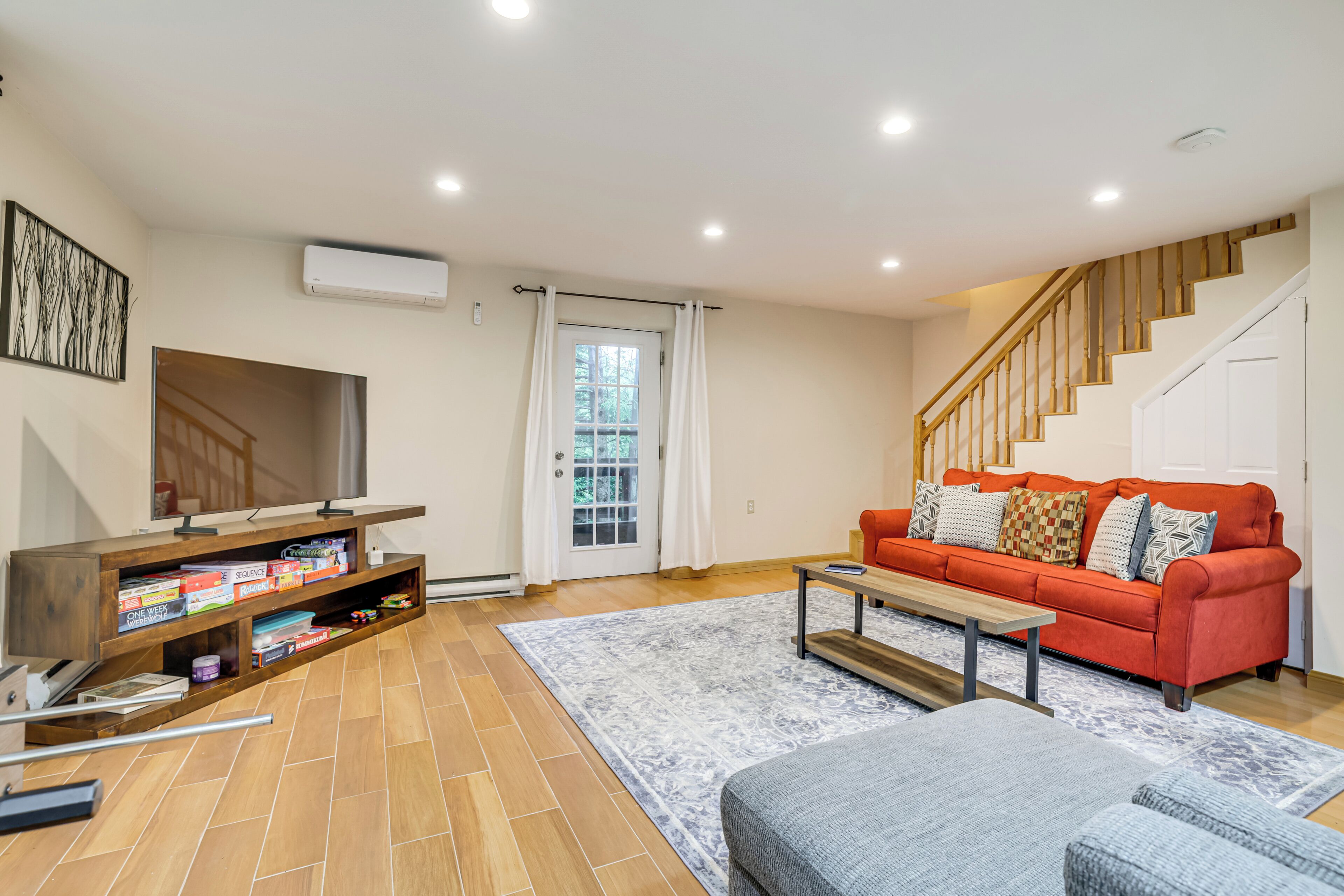 Una sala de estar con televisor, sofá, mesa de centro y una escalera.