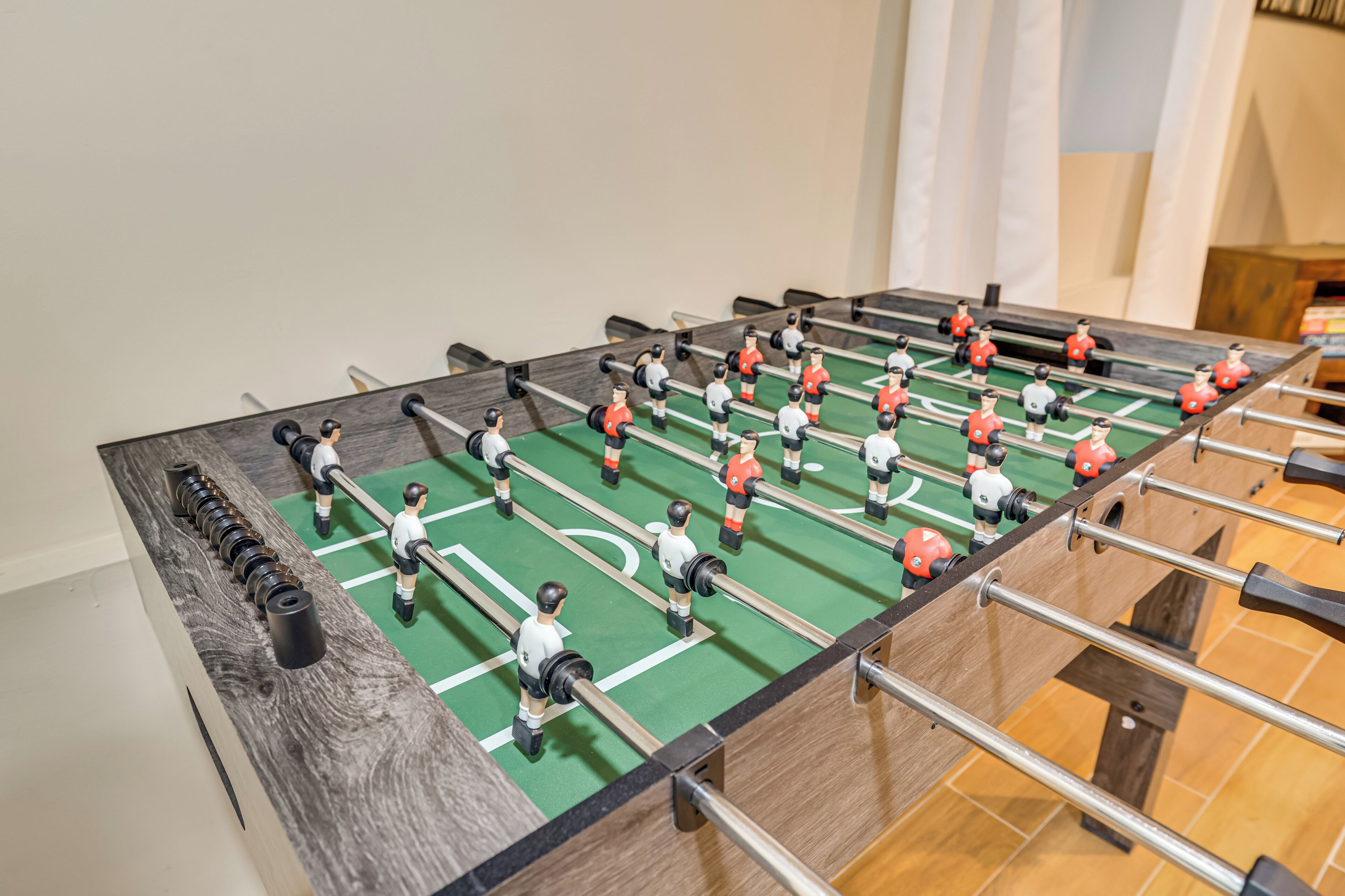 Une table de baby-foot avec plusieurs joueurs, une table en bois et une surface de jeu verte.