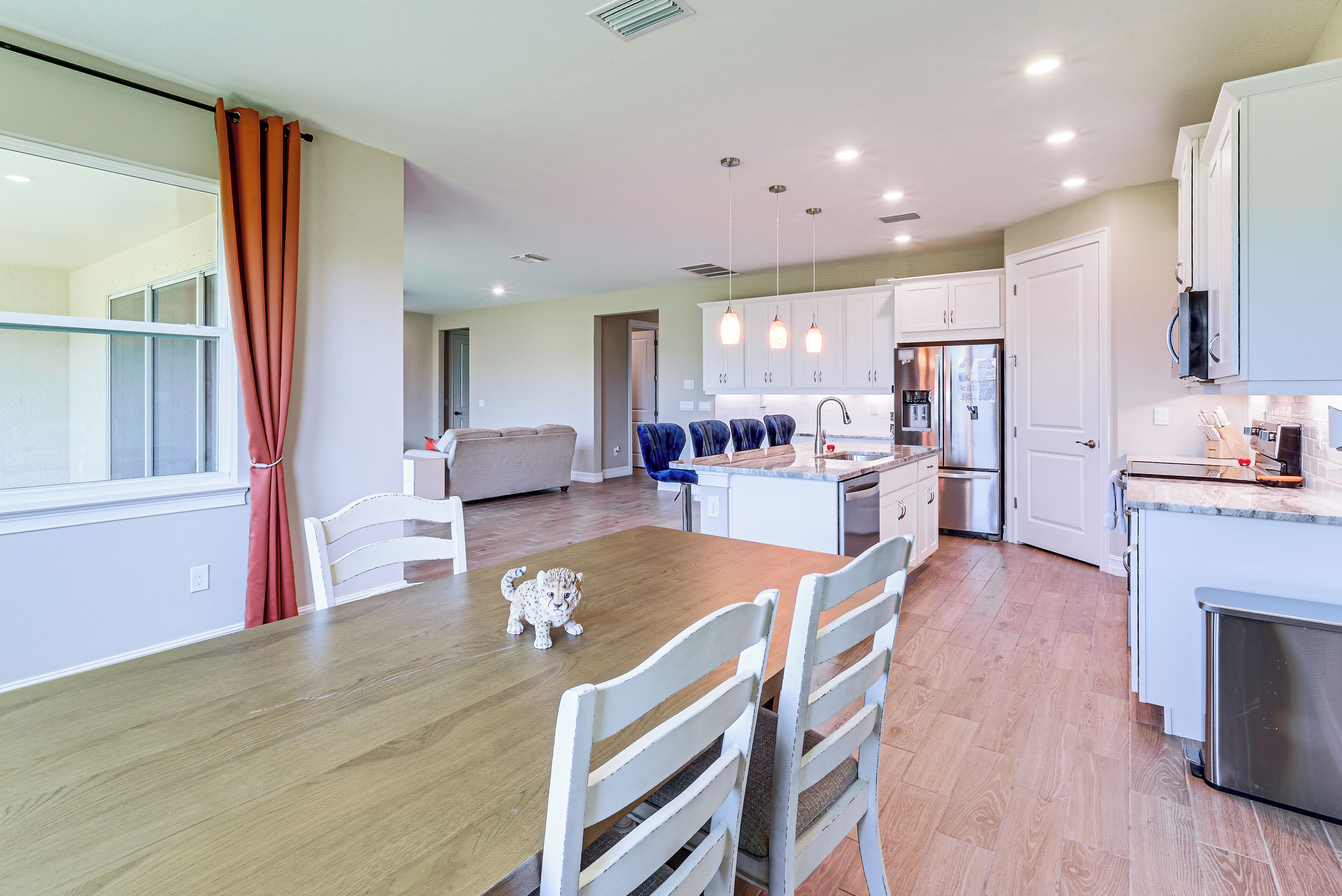Una cocina moderna con armarios blancos, una mesa de comedor de madera y una pequeña figura de leopardo.