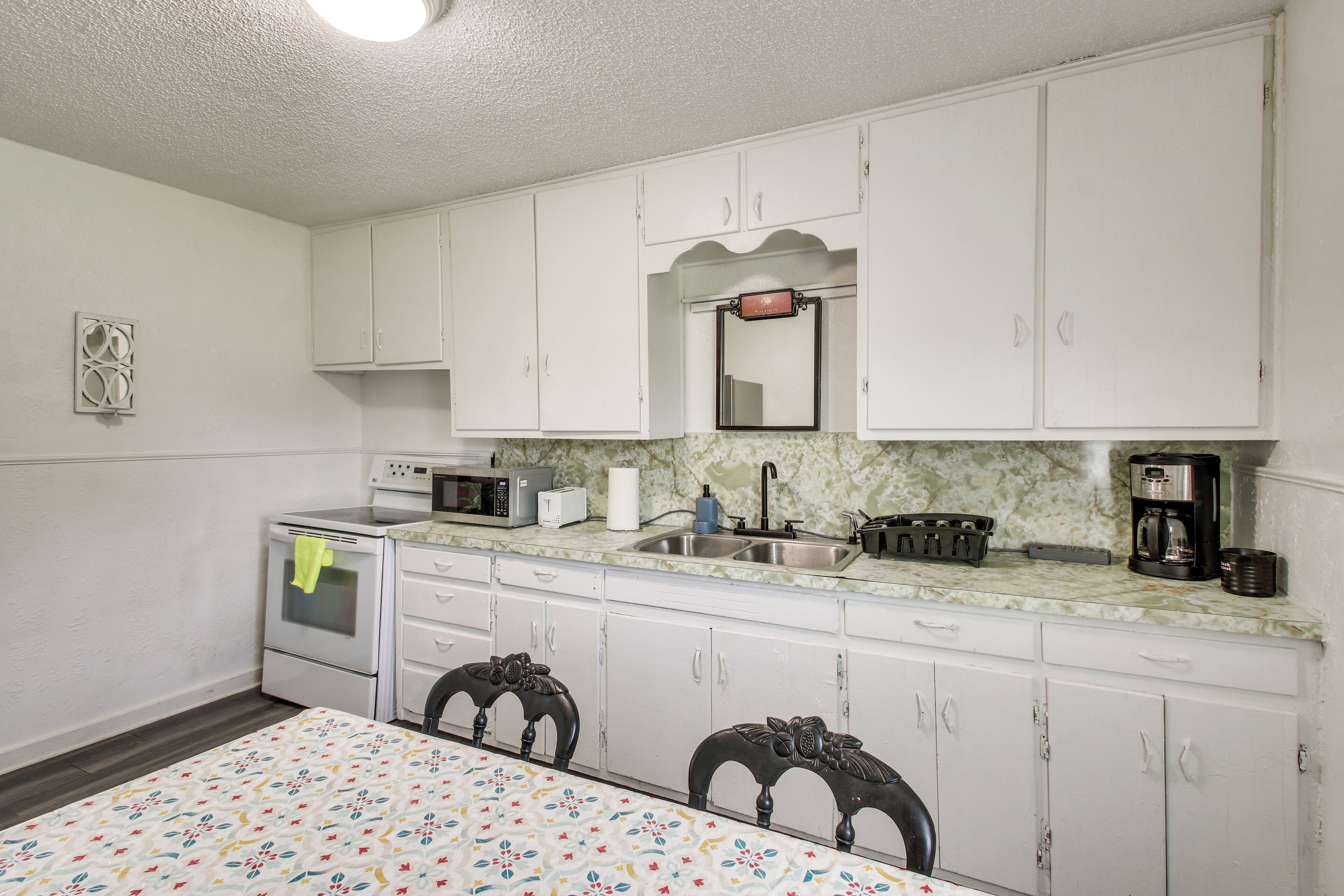 A kitchen with white cabinets, a microwave, a sink, and a dining table with chairs.