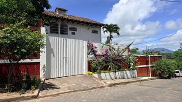 A residential house with a gated entrance, a tiled roof, and a paved driveway.