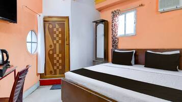 A bedroom with a bed, a TV, a mirror, a window with curtains, and a door with a geometric design.