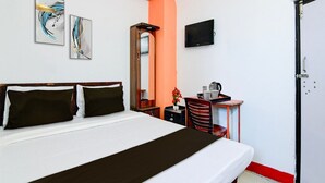 A hotel room with a bed, a desk with a mirror, a television, and artwork on the walls. - Classic Hotel Ameesha Lodge (Barakpur)