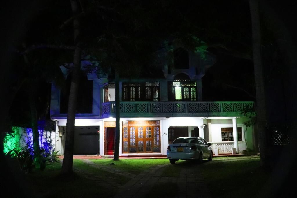 A two-story building with a car parked in front, surrounded by trees.
