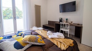 Ein Hotelzimmer mit Bett, Schreibtisch, Stuhl, Fernseher und einem fensterbepflanzten Fenster.
