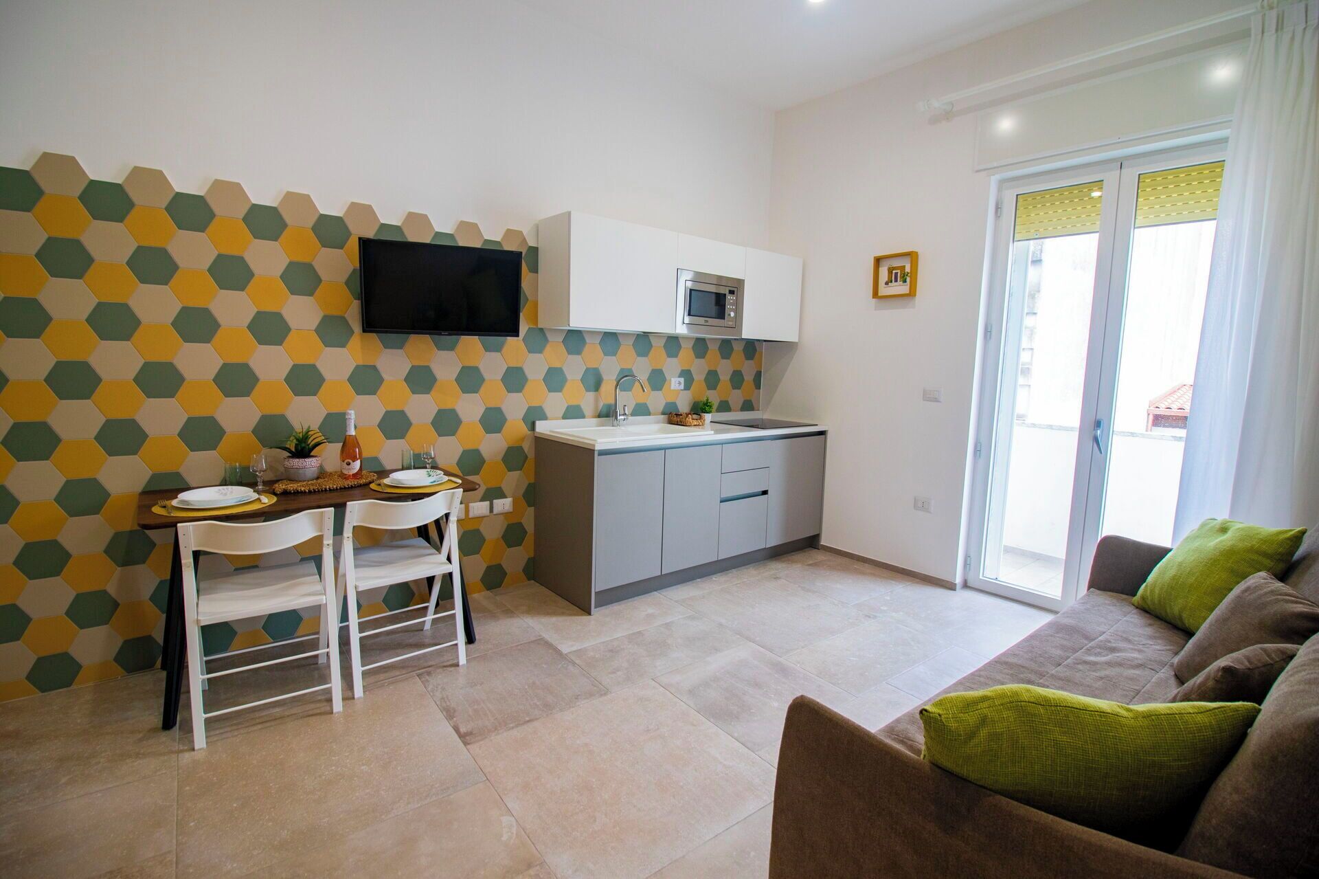 A compact living space with a dining area, kitchenette, and a sofa with cushions.