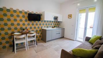 A compact living space with a dining area, kitchenette, and a sofa with cushions.