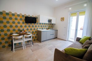 Un espacio habitable compacto con comedor, kitchenette y sofá con cojines.