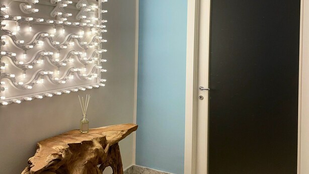 Ein Zimmer mit einer Wandleuchte, einem Holztisch und einer Tür mit der Aufschrift 'ELEMENTI LUXURY HOUSE'.