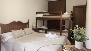 Un dormitorio con una cama litera, una mesita de noche con lámpara, una planta en maceta y una revista en el suelo.