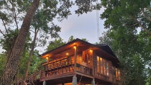 A wooden cabin with a balcony, surrounded by trees.