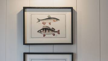 Dos ilustraciones enmarcadas de peces en una pared, con una lámpara horizontal en la parte superior.