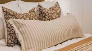 A neatly made bed with patterned pillows and a striped blanket.