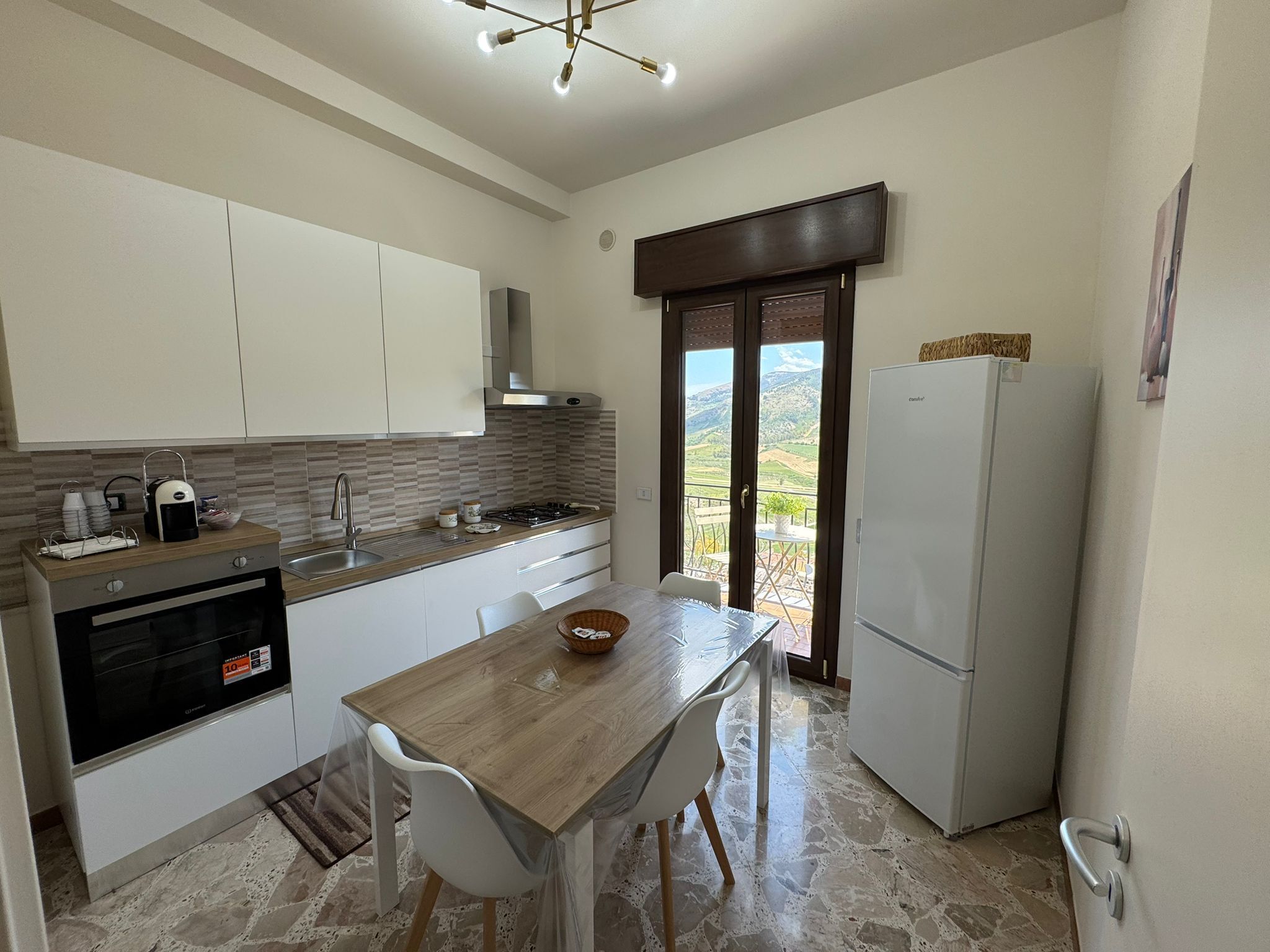 Een moderne keuken met witte kastjes, een houten tafel en een koelkast.