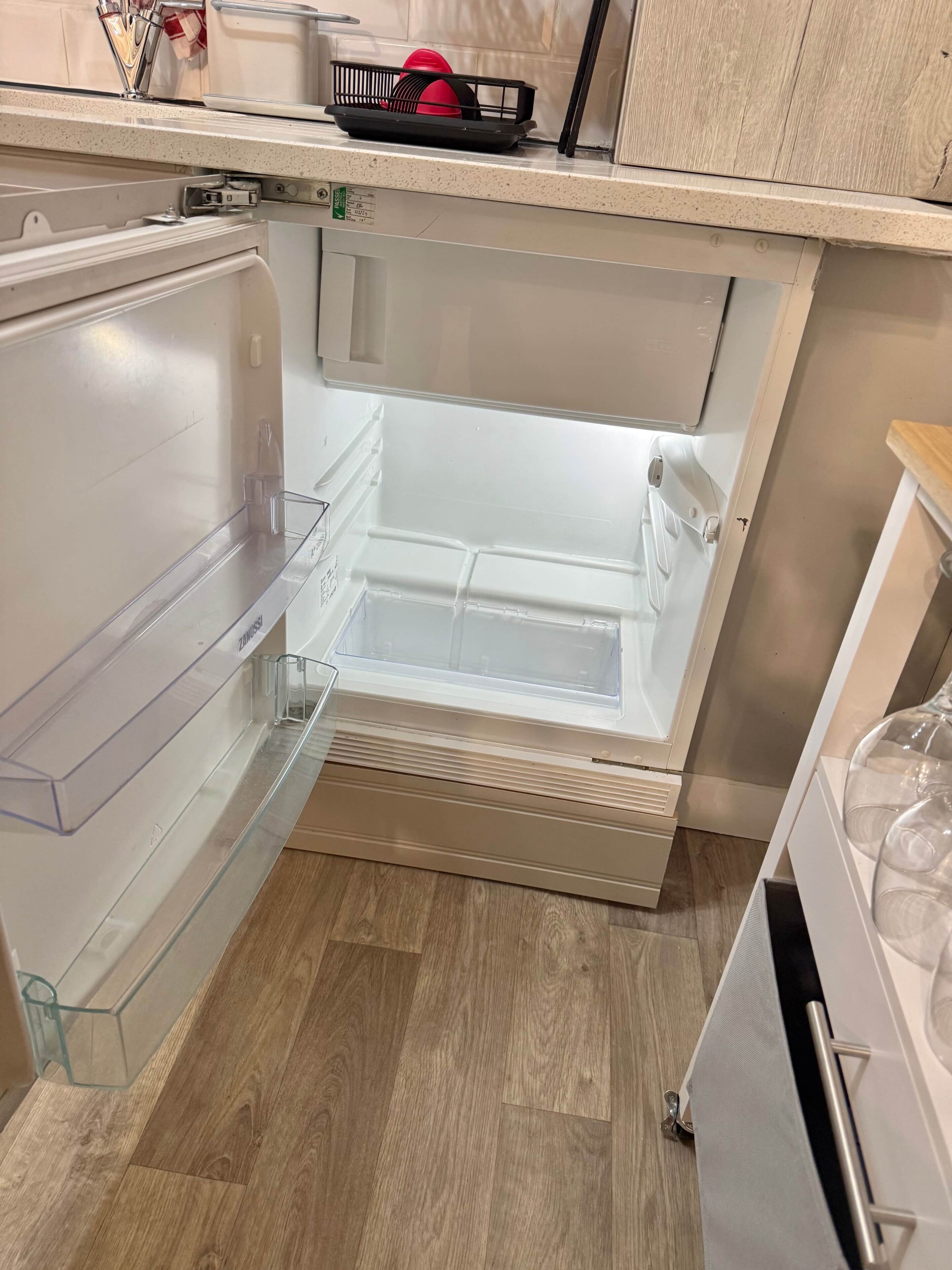Una cocina con refrigerador empotrado, una encimera y piso de madera.