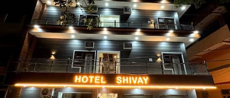 A multi-story hotel with a prominent 'HOTEL SHIVAY' sign, balconies, and potted plants.