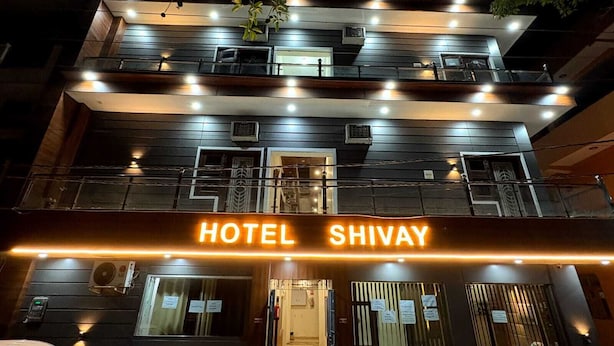 Un edificio de varios pisos con un letrero que dice 'HOTEL SHIVAY' en la entrada.