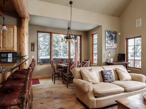 Ein gemütliches Interieur mit einem Holzesstisch, einer Couch und einer Küchenzeile mit einer Bar.