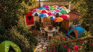 Un jardín con una mesa, sillas, una tienda de campaña y sombrillas coloridas.