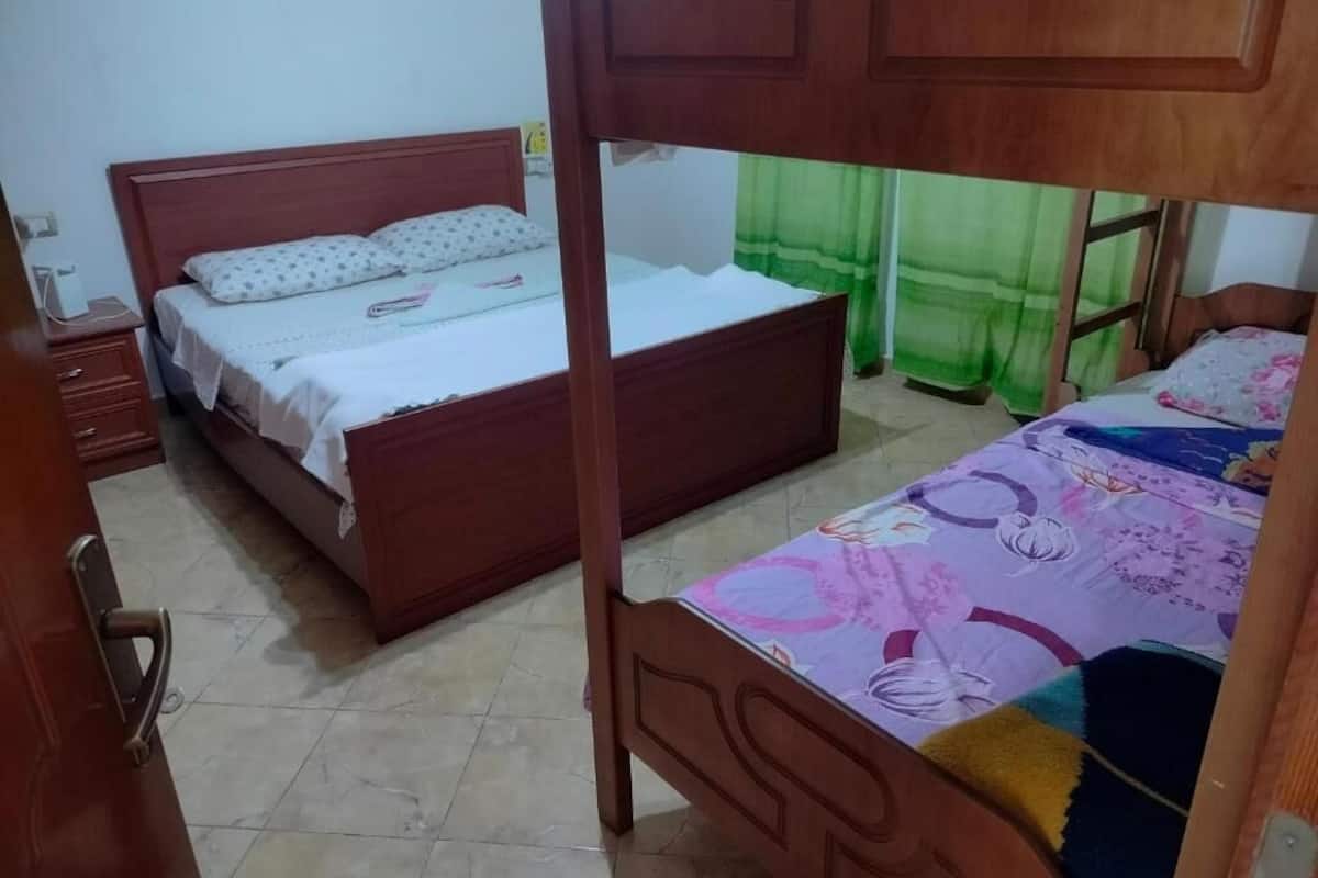 A room with two wooden beds, a nightstand, and a door.