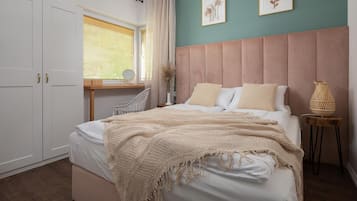 A bedroom with a bed, bedside table, lamp, and artwork on the wall.