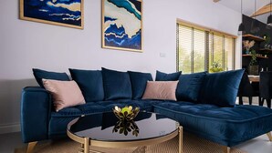 A modern living room with a dark blue sectional sofa, a round glass coffee table, and abstract wall art. - Comfortable Holiday Home, Pool, Sauna, Jacuzzi (Krokowa)