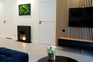 Una sala moderna con chimenea, televisor de pantalla plana y un sofá.