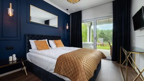 A bedroom with a large bed, a bedside table, a TV, and a view of the outdoors. - Comfortable Holiday Home, Pool, Sauna, Jacuzzi (Krokowa)