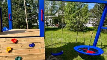 A playground with climbing holds, a swing set, and a trampoline.
