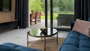 A modern living room with a TV, sofa, and glass table. - Comfortable Holiday Home, Pool, Sauna, Jacuzzi (Krokowa)