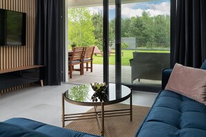 A modern living room with a TV, sofa, and glass table. - Comfortable Holiday Home, Pool, Sauna, Jacuzzi (Krokowa)