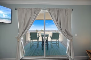 A balcony with a view of the beach, a table, and two chairs. - Condo Near Beach with Pool by PKRM (Pensacola)