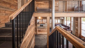 A wooden interior with a staircase, a balcony, and a kitchen area. - Modern Chalet in the Willow Roof (Leutasch)