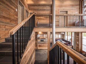 Un interior de madera con escalera, balcón y área de cocina.