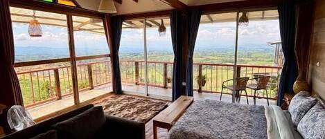 A room with a bed, a sofa, a small table, and a view of the outdoors.