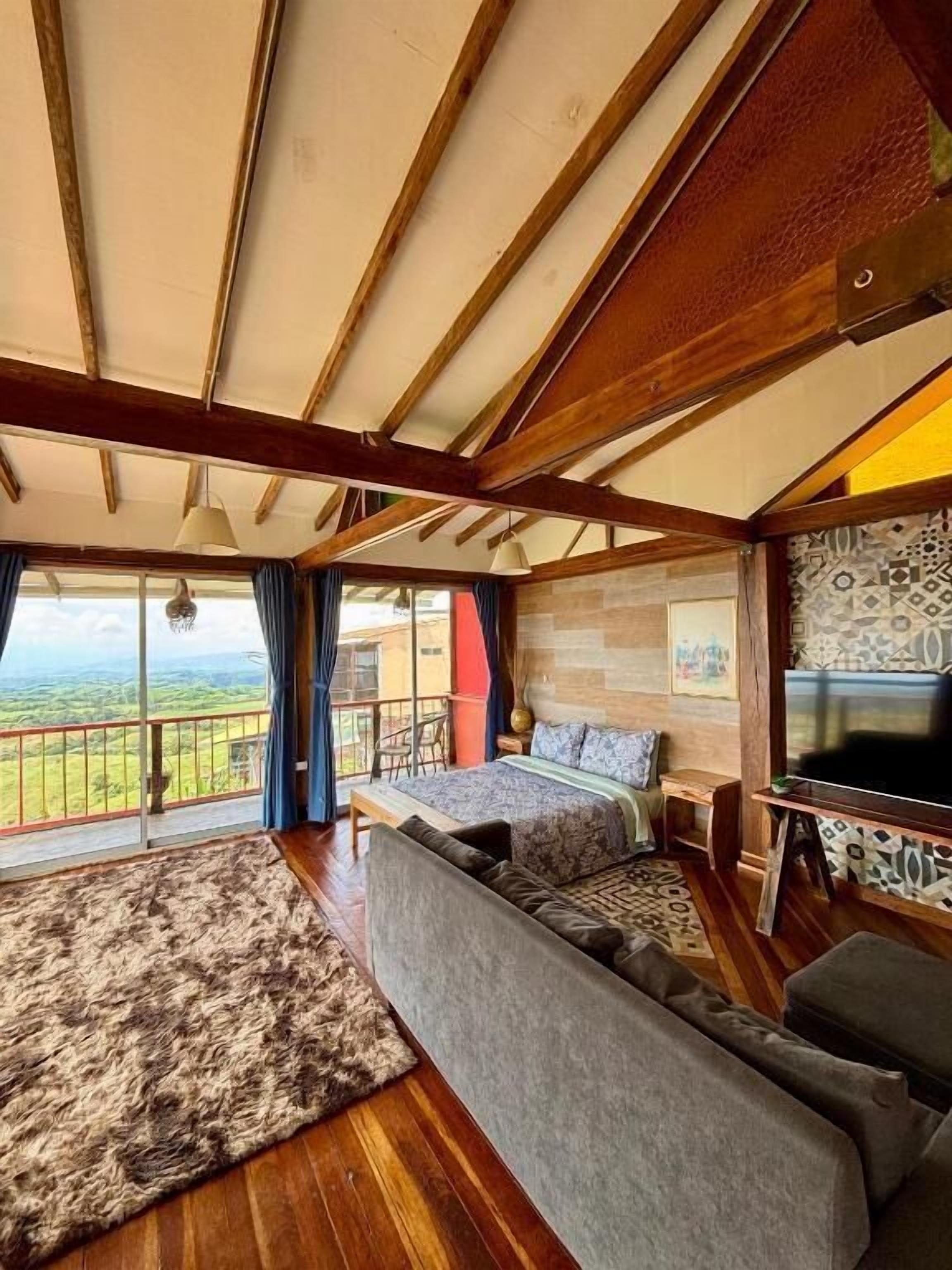 Una habitación con una cama grande, un sofá, un televisor y vistas al exterior.