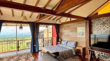 Una habitación con una cama grande, un sofá, un televisor y vistas al exterior.