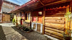 Un edificio rústico de madera con un camino de piedra, contraventanas de madera y plantas en macetas.