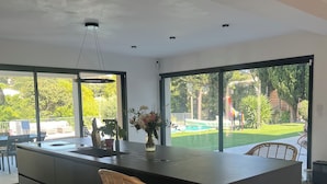 A modern kitchen with a large island, bar stools, and a view of a garden. - Exceptional home with a pool (La Seyne-sur-Mer)