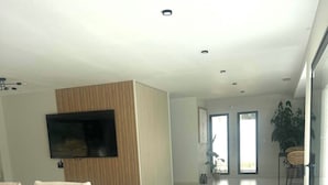 A spacious living area with a large flat-screen TV, a sectional sofa, and a modern kitchen visible through an open door. - Exceptional home with a pool (La Seyne-sur-Mer)