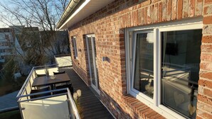 Ein Ziegelhaus mit Balkon, einem Tisch und einem Stuhl.