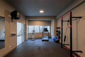 A home gym with a treadmill, exercise bike, weight bench, and a pull-up bar. - MOT Rentals + Concepcion Hotel - 3 Bd 2 Ba Parking, Gym and Pool (Buenos Aires)