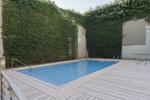 A rectangular swimming pool with a wooden deck surrounding it, enclosed by a high hedge. - MOT Rentals + Concepcion Hotel - 3 Bd 2 Ba Parking, Gym and Pool (Buenos Aires)