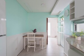 A kitchen with white cabinetry, a dining table with chairs, and a window with a plant. - MOT Rentals + Concepcion Hotel - 3 Bd 2 Ba Parking, Gym and Pool (Buenos Aires)