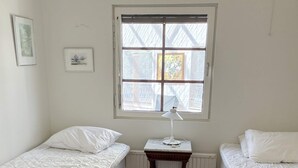 A room with two single beds, a radiator, a window with blinds, and a small table with a lamp. - 4 Star Holiday Home in Gotlands Tofta (Gotlands Tofta)