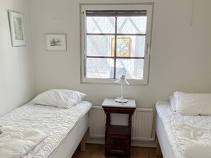 A room with two single beds, a radiator, a window with blinds, and a small table with a lamp. - 4 Star Holiday Home in Gotlands Tofta (Gotlands Tofta)