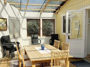 A sunlit room with a wooden table, chairs, a blue vase, and a door with a window. - 4 Star Holiday Home in Gotlands Tofta (Gotlands Tofta)