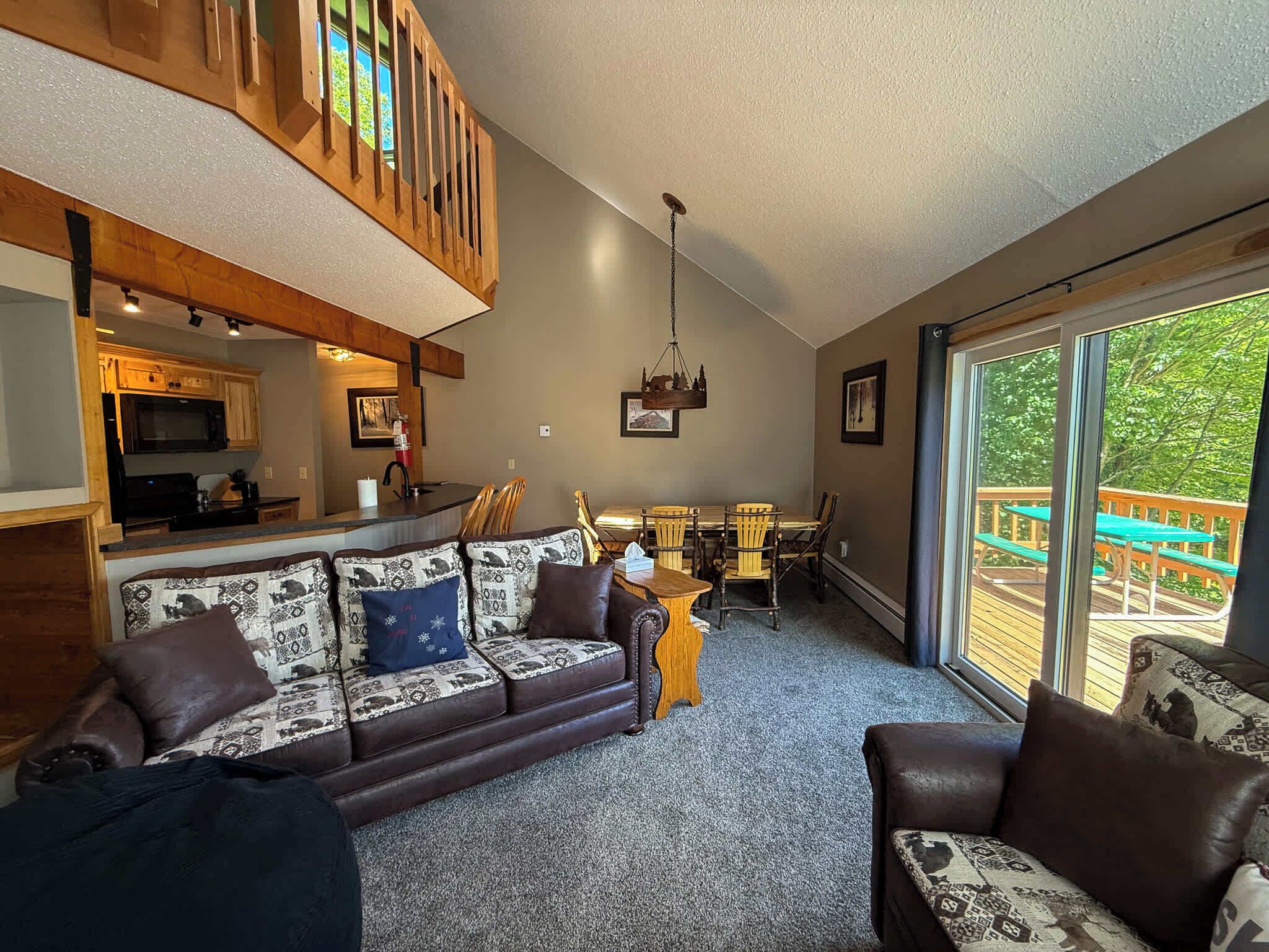 A cozy living room with a sofa, a dining table, and a kitchen in the background.
