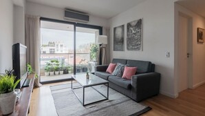 A modern living room with a sofa, coffee table, and potted plants. - MOT Concepcion Arenal (Buenos Aires)